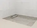 Installation d'un receveur de douche entre trois murs, avec évacuation visible.