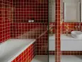 Salle de bain aux carreaux rouges vifs. La question "faut il carreler toute la salle de bain" se pose face à cette audace. Baignoire, lavabo et douche sont intégrés.