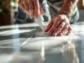 Application de joint blanc sur du carrelage sur placo. Les mains travaillent avec précision pour un résultat impeccable.