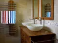 Salle de bain moderne avec double vasque. L'arrivée d'eau est discrète, deux lavabos blancs reposent sur un meuble en bois. Deux serviettes rayées sèchent sur un radiateur.