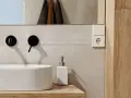 Évier moderne avec robinetterie noire, distributeur de savon et prise électrique. Un détail de la sécurité de la salle de bain.