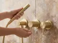 Mains dorées ajustant le débit d'eau d'une robinetterie de salle de bain en laiton, pour un nettoyage chrome salle de bain impeccable.