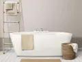 Baignoire moderne avec robinetterie chromée. Un porte-serviettes en bois et un panier en osier complètent l'ensemble, suggérant un émail baignoire poreux à l'aspect naturel.