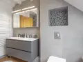 Salle de bain moderne avec double vasque, radiateur blanc et un choix carrelage gris subtil, agrémenté d'une niche décorative en mosaïque.