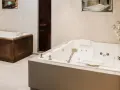 Deux baignoires modernes, une habillée de bois, l'autre d'un revêtement gris, illustrent comment habiller une baignoire avec style.
