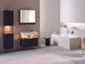 Salle de bain moderne avec baignoire, lavabo et meubles suspendus. Le sol en béton poli et le carrelage mural clair facilitent le nettoyage.