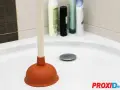 Plongeur dans une douche bouchée avec de l'eau stagnante. Des bouteilles de shampoing sont visibles en arrière-plan.
