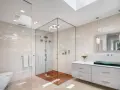 Salle de bain moderne avec douche italienne spacieuse, sol en bois, murs en mosaïque et lavabo design.
