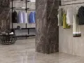 Un dressing moderne avec des vêtements suspendus, un fauteuil noir et un sol en lappato carrelage aux tons taupe.