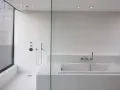 Salle de bain moderne avec douche à l'italienne et baignoire îlot, le tout revêtu de petites mosaïques blanches.