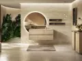 Une **salle de bain chic et cosy** avec un meuble vasque en bois clair, un grand miroir rond lumineux, des plantes luxuriantes et une ambiance apaisante.