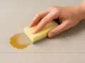 Main tenant une éponge jaune pour nettoyer une tache sur du carrelage. L'acétone peut être utile pour certaines taches tenaces sur le carrelage.