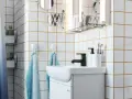 Salle de bain moderne avec carrelage blanc joint gris, lavabo, robinetterie noire et accessoires pratiques.
