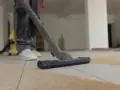 Nettoyage de carrelage après chantier : un aspirateur passe sur le sol poussiéreux.