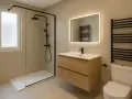 Salle de bain moderne avec douche à l'italienne, meuble vasque en bois, miroir lumineux et radiateur noir. Une belle idée salle de bain douche.