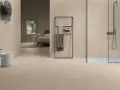 Salle de bain moderne avec bidet, douche et lit visible au loin, le tout revêtu de grès cérame émaillé.