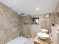 Salle de bain moderne avec une belle installation douche, deux lavabos et un dressing ouvert.