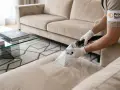 Nettoyage d'un canapé beige avec un appareil d'extraction, comme si l'on traitait du carrelage poreux pour enlever les taches.