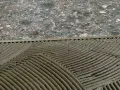 Pose de mortier pour un double encollage de carrelage. Les mains d'un carreleur préparent la surface.