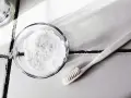 Bicarbonate de soude dans un bol et une brosse à dents sur un carrelage.