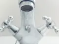 Gouttes d'eau tombant d'un robinet chromé. Comprendre la différence entre mitigeur et mélangeur pour une meilleure gestion de l'eau.