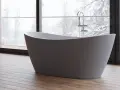 Baignoire îlot moderne, avec robinetterie chromée, devant une grande fenêtre donnant sur un paysage hivernal. Les inconvénients de ce type de baignoire sont son encombrement et la nécessité d'une installation spécifique.