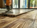 Pose d'un carrelage sur un parquet. Un outil aide à coller le carrelage sur bois, créant une nouvelle surface.