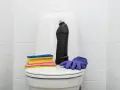 Produits de nettoyage pour les toilettes : une bouteille de produit, des éponges et des gants violets. Une astuce de grand-mère pour détartrer les wc.