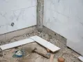 Travaux de pose de faience salle de bain : des carreaux de marbre blanc sont prêts à être installés, avec des outils au sol.