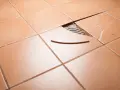 Carrelage orange avec une tuile cassée et un éclat à réparer.