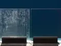 Comparaison de deux parois de douche : l'une est recouverte de dépôts calcaires incrustés, l'autre est parfaitement propre et transparente.