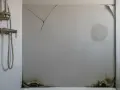Panneau mural de douche fissuré, taché et moisi, illustrant les inconvénients de ce type de revêtement.