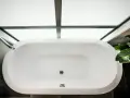 Vue aérienne d'une baignoire blanche moderne, prête à accueillir un bain relaxant. La contenance baignoire est généreuse, sous un puits de lumière.