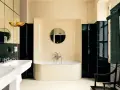 Élégante salle de bain noir et blanc avec baignoire îlot, lavabo double vasque et carrelage brillant.