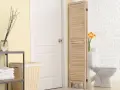 Un paravent en bois crée une séparation toilette salle de bain, cachant le WC derrière une porte blanche.