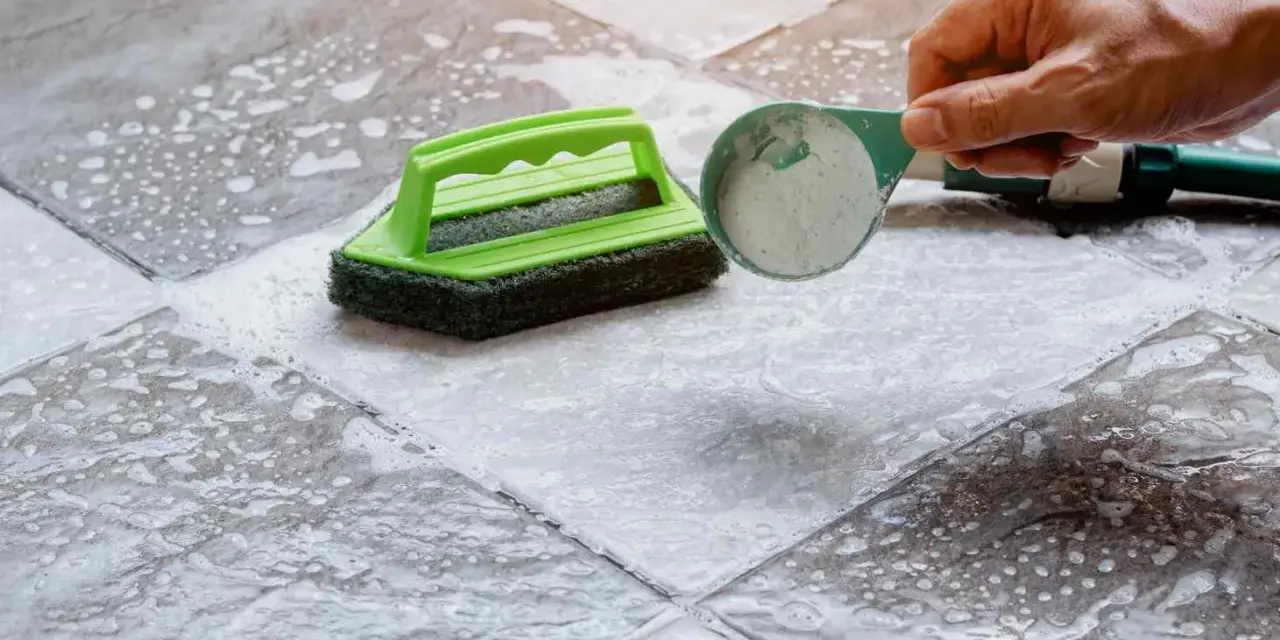 Nettoyer un carrelage mat et poreux avec une brosse et une poudre nettoyante.