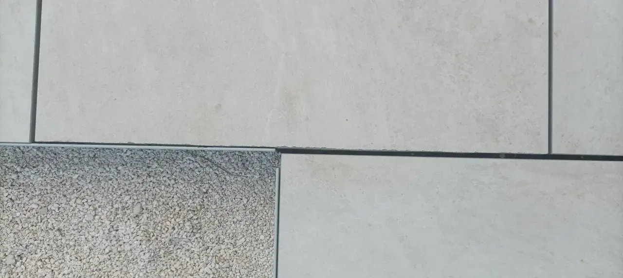 Détail d'un sol extérieur avec des dalles claires et une zone de gravier, montrant la précision du couper carrelage.