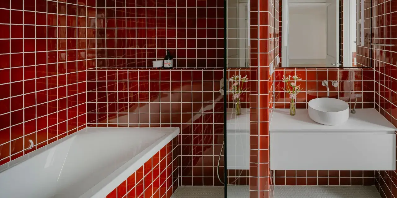 Salle de bain aux carreaux rouges vifs. La question "faut il carreler toute la salle de bain" se pose face à cette audace. Baignoire, lavabo et douche sont intégrés.