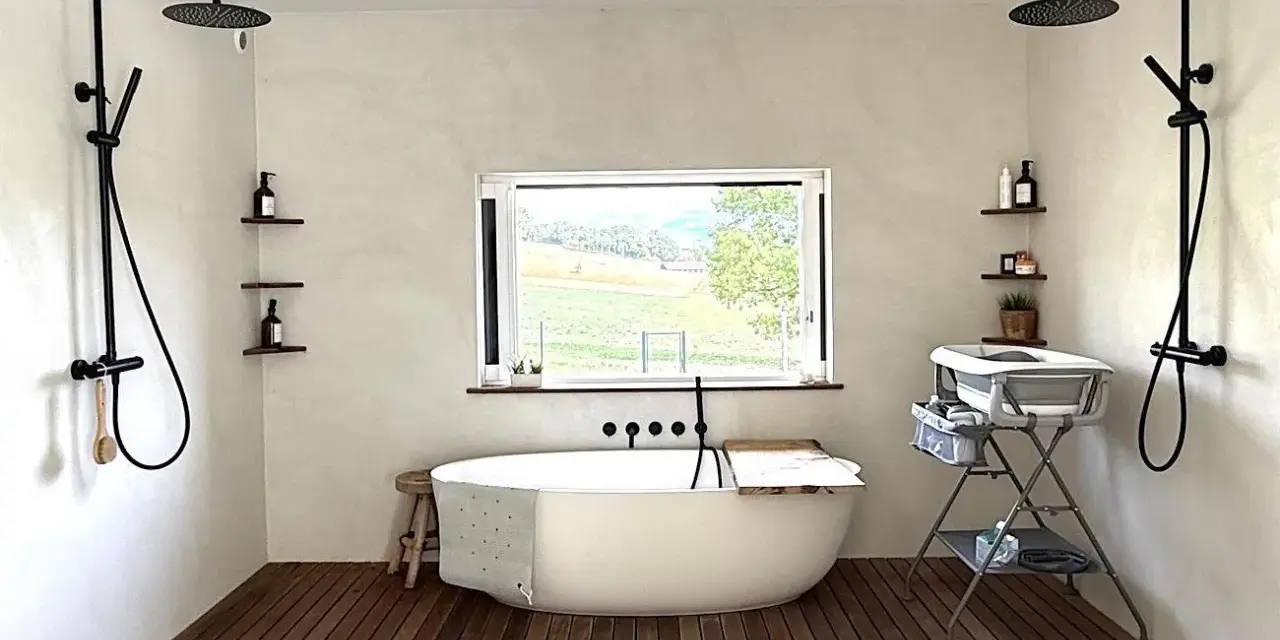 Une **salle de bain intemporelle** avec baignoire îlot, deux douches murales, et une vue sur la campagne.