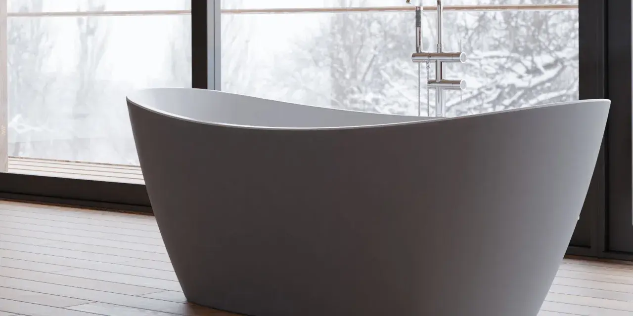 Une baignoire moderne dans une chambre, avec une grande fenêtre offrant une vue sur un paysage enneigé. Parfait pour un moment de détente.