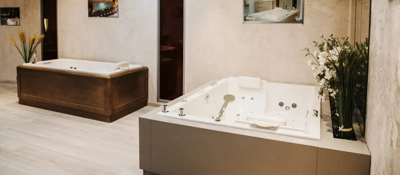 Deux baignoires modernes, une habillée de bois, l'autre d'un revêtement gris, illustrent comment habiller une baignoire avec style.