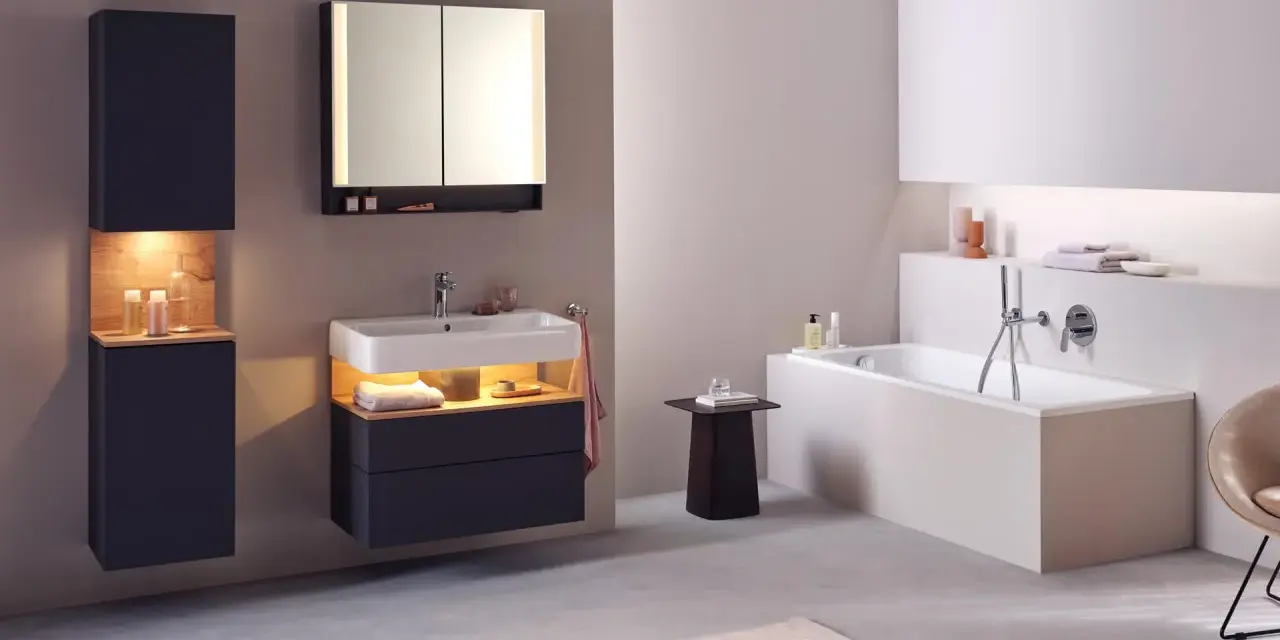 Salle de bain moderne avec baignoire, lavabo et meubles suspendus. Le sol en béton poli et le carrelage mural clair facilitent le nettoyage.
