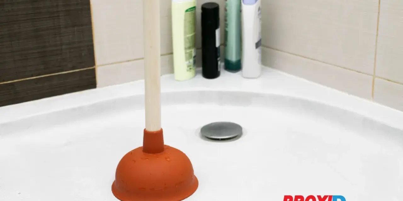 Plongeur dans une douche bouchée avec de l'eau stagnante. Des bouteilles de shampoing sont visibles en arrière-plan.