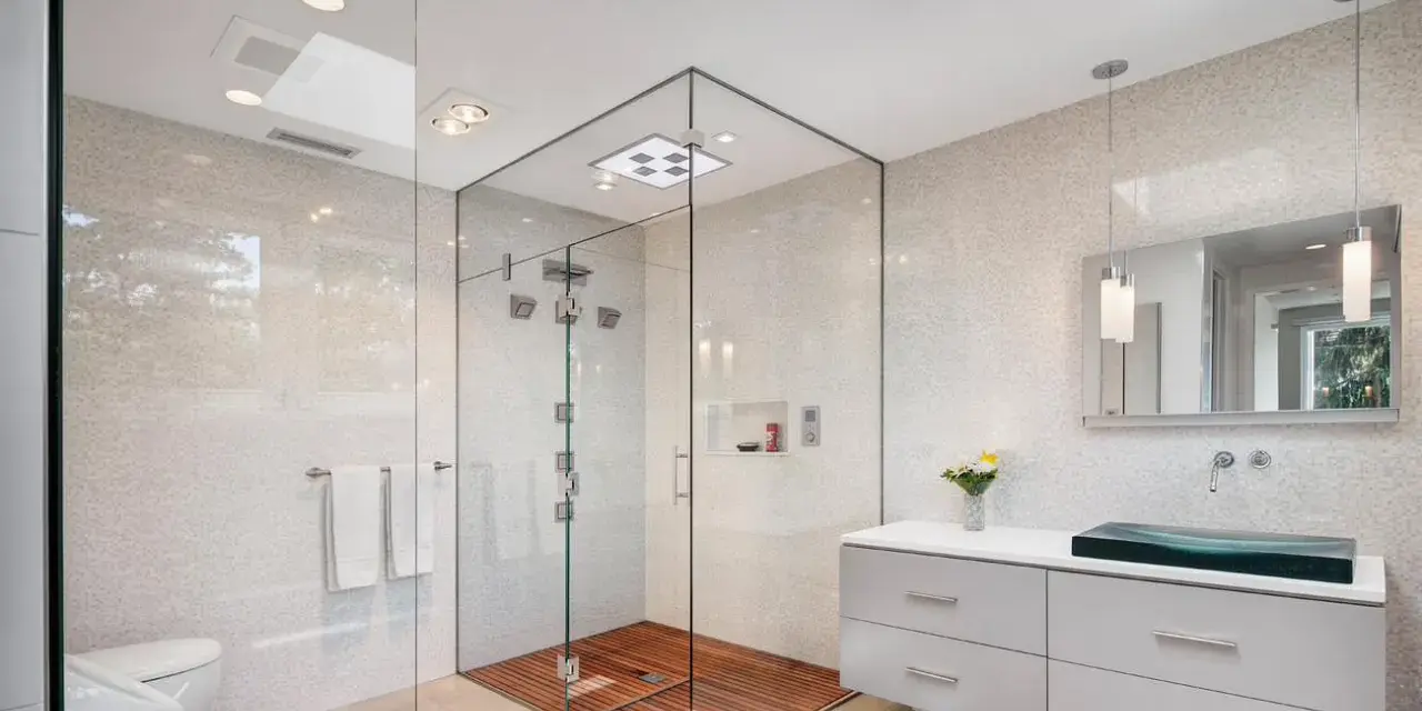 Salle de bain moderne avec douche italienne spacieuse, sol en bois, murs en mosaïque et lavabo design.