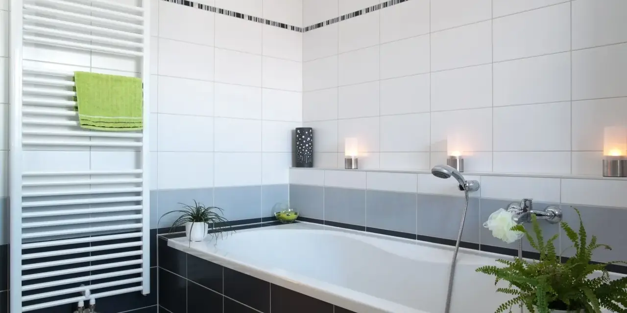 Salle de bain moderne avec baignoire, radiateur blanc et carrelage impeccable. Les joints de carrelage sont parfaits, donnant une finition propre.
