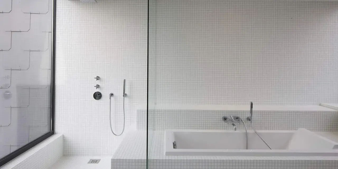 Salle de bain moderne avec douche à l'italienne et baignoire îlot, le tout revêtu de petites mosaïques blanches.