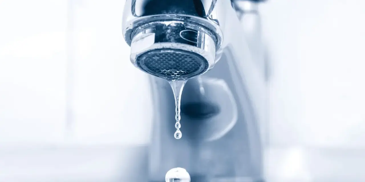 Gouttelettes d'eau tombant d'un robinet de salle de bain qui fuit. Un petit désagrément qui coûte cher.