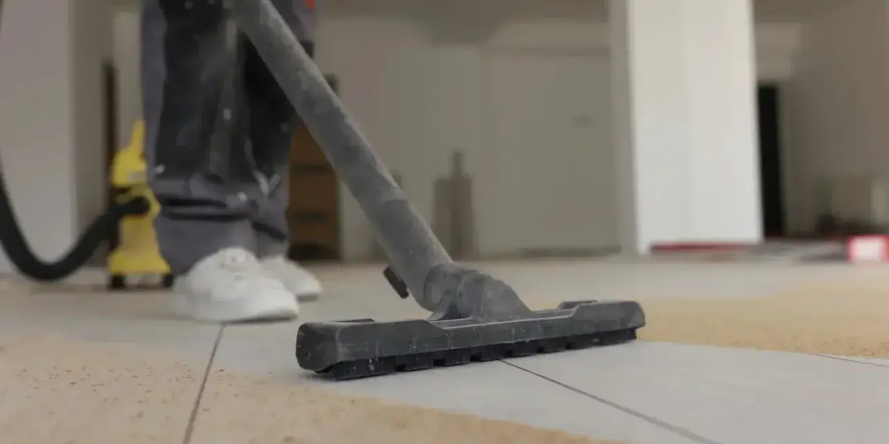 Nettoyage de carrelage après chantier : un aspirateur passe sur le sol poussiéreux.