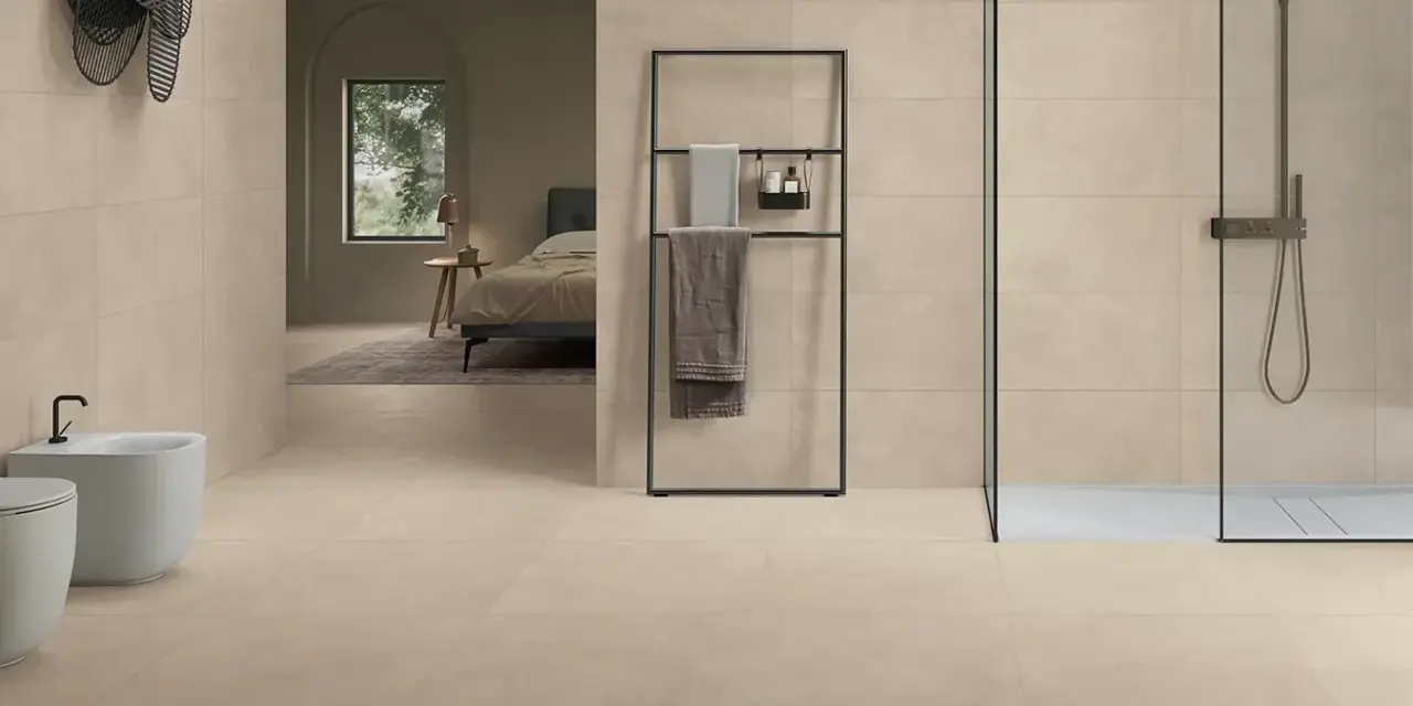 Salle de bain moderne avec bidet, douche et lit visible au loin, le tout revêtu de grès cérame émaillé.