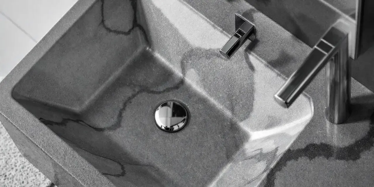 Évier en béton gris avec des veines sombres, robinetterie moderne. La différence évier lavabo est subtile, mais ici, c'est un lavabo design.
